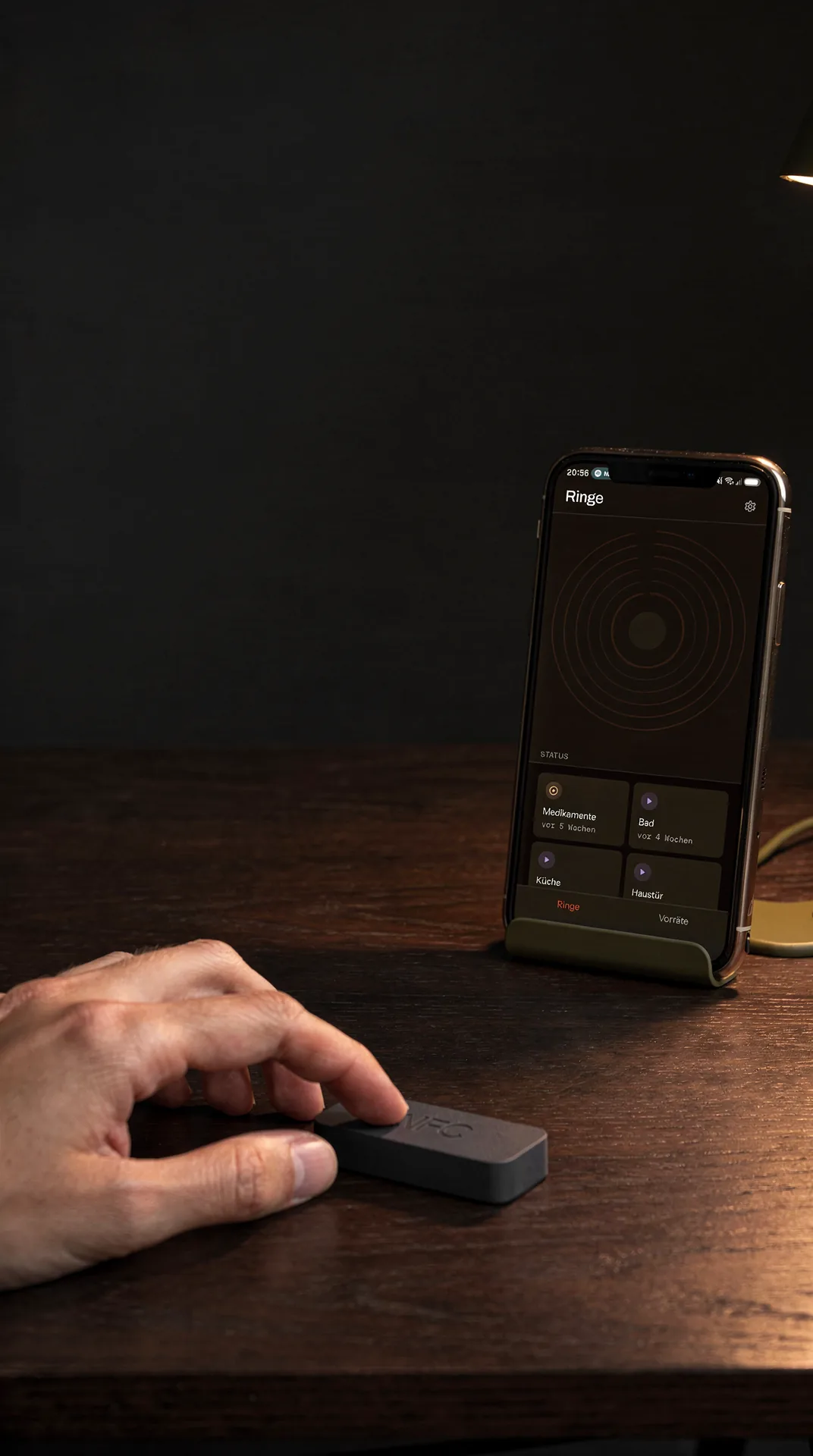 Telefon auf einem Schreibtisch zeigt den Ringe-Bildschirm von Permy mit Wachstumsringen und Statuskacheln, daneben eine Hand am NFC-Tag.